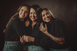 Cheerful studio portraits of Mom and her two daughters in Las Vegas with black blouses and blue jeans