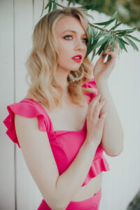 Beautiful fashion photography of young woman wearing pink upon a white picket fence