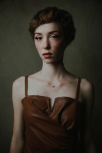 Dramatic Fashion forward portrait of young woman with short red hair and blush cheeks