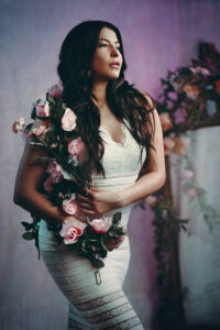Creative beauty fashion portrait in studio with flowers and elegant white form fitting dress