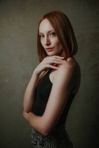 Simple elegant studio portrait of red headed woman in editorial style