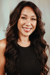 Glowing and happy headshot of woman with curly hair and black dress
