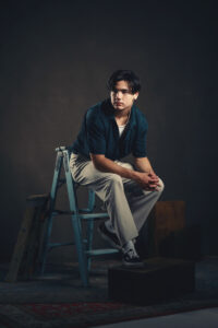 Trendy senior graduation portrait with white pants and blue button up shirt sitting on a ladder